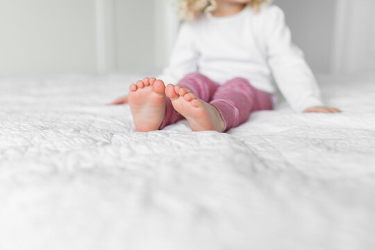 Close up of the bare feet of young girl wearing red and white pajamas