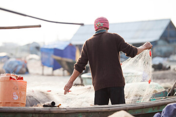 Fishermen repairing nets on a boat trip out to sea in the afternoon July 31, 2014 at the beach of Hai Ly, Vietnam.