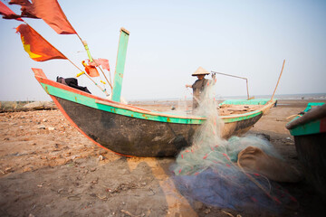 Fishermen repairing nets on a boat trip out to sea in the afternoon July 31, 2014 at the beach of...