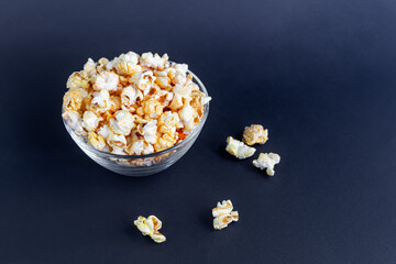 A clear bowl of popcorn on the darkened surface.