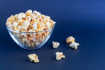 A clear bowl of popcorn on the darkened surface.