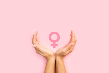 Manos de mujer con cartel de género femenino sobre fondo rosa pastel liso y aislado. Vista...