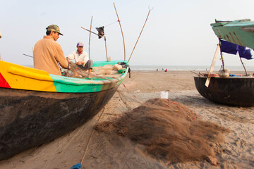 Fishermen repairing nets on a boat trip out to sea in the afternoon July 31, 2014 at the beach of...