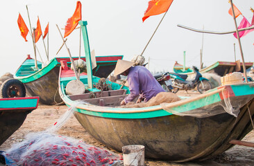 Fishermen repairing nets on a boat trip out to sea in the afternoon July 31, 2014 at the beach of Hai Ly, Vietnam.
