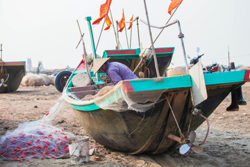 Fototapeta na wymiar Fishermen repairing nets on a boat trip out to sea in the afternoon July 31, 2014 at the beach of Hai Ly, Vietnam.