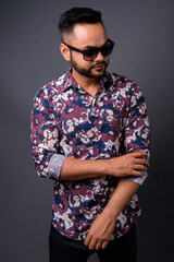 Young bearded Indian man against gray background