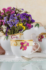 Obraz na płótnie Canvas Morning tea in beautiful cups and bright dried flowers on delicate beige background