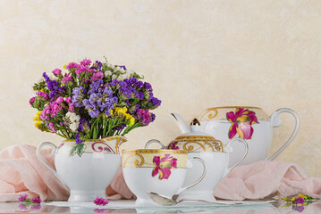 Beautiful exquisite tea set decorated with a beige napkin and dried flowers