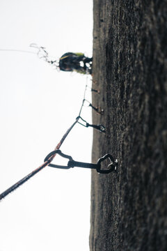 Mountaineer rock climbing a wall with the view of all the climbing quickdraws below him