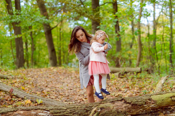 Mother holds daughter in her arms in the park on a sunny day. Autumn day.