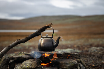 Camp kettle is heated on a bonfire. Hiking, travel in the mountains. Outdoor recreation concept....