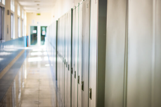 Empty hallway corridor of a high school or college closed during COVID-19 (Coronavirus). Lockers blurred into lonely hallway.