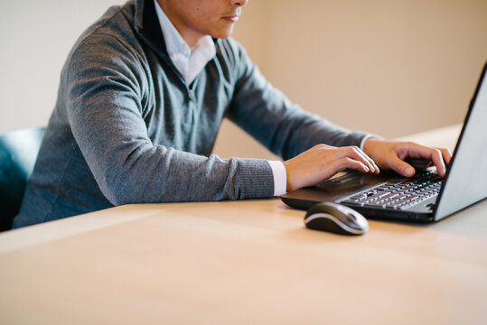 asian man types on laptop computer