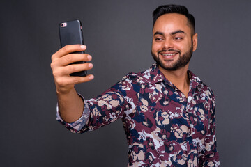 Young bearded Indian man against gray background