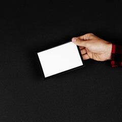 Photo frame in hands on a black background. Preparation for text, mockup, copy space.