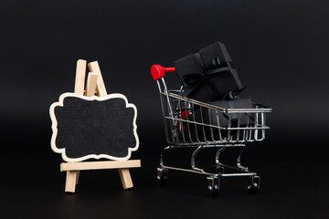 A frame and shopping cart with gifts on black background, a blank for the design, concept. Copy...