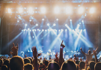 Crowd enjoying and putting hands in the air at a music festival with moving lights