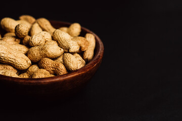 peanuts in a wooden plate on a black background