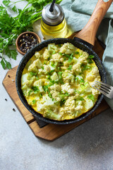 Healthy breakfast or diet lunch. Egg omelet with cauliflower in a cast-iron pan on a light stone table top. Copy space.