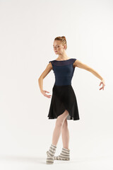 woman ballerina in pointe shoes and in a tutu dances on a light background in full growth 