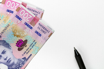 hryvnia and pen on a blank sheet of notepad, space for text