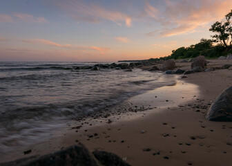 rocky sea shore before sunrise, dark stone silhouettes and colorful sky