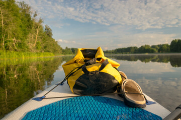 lake shore view, foreground sup board bow with yellow waterproof bag, summer