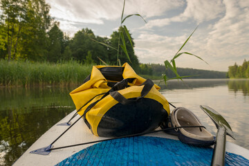 lake shore view, foreground sup board bow with yellow waterproof bag, summer