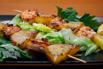 tiger prawns with pineapples in a black plate