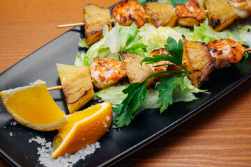 tiger prawns with pineapples in a black plate