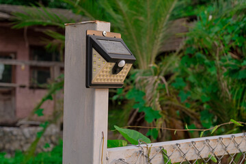Old solar light lamp hank on fence.