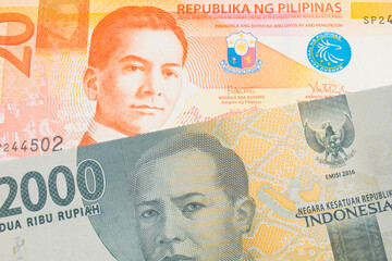 A macro image of a grey two thousand Indonesian rupiah bank note paired up with a orange and white twenty piso note from the Philippines.  Shot close up in macro.