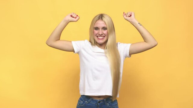 Young caucasian blonde woman celebrating a special day, jumps and raise arms with energy