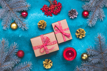 Christmas tree with gifts on a blue background. Happy New Year composition with red and gold balls, fir branches, a burning candle, viburnum berries. Merry Xmas greeting card.