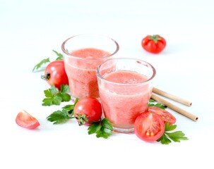 Fresh tomato juice in a glass with bamboo straws on a white background