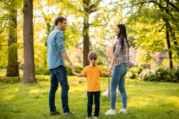 Obraz premium Happy family with cute bichon dog in the park