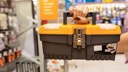Woman holding orange heavy duty plastic tool box at the store