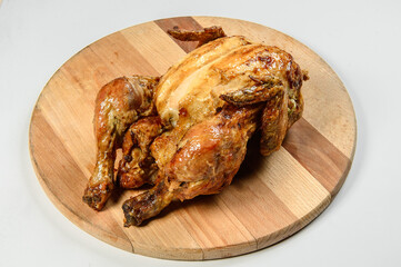 Whole Grilled chicken on round wooden cutting board isolated on background. Restaurant menu dish isolation. Meat on wooden board 
