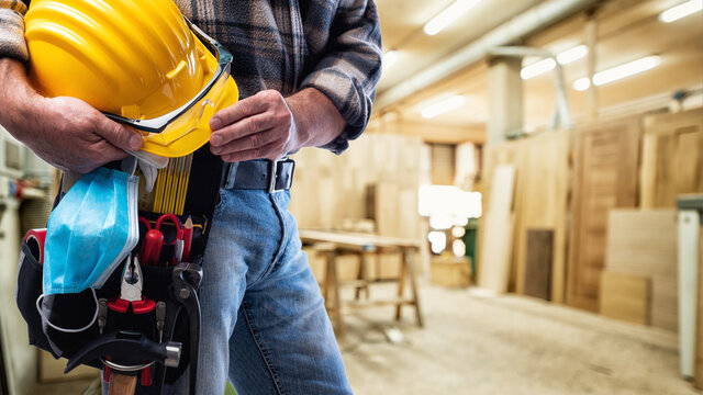 Carpenter with work tools and surgical mask on white background. Carpentry. Covid-19 prevention.
