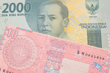 A macro image of a grey two thousand Indonesian rupiah bank note paired up with a red ten taka bank note from Bangladesh.  Shot close up in macro.