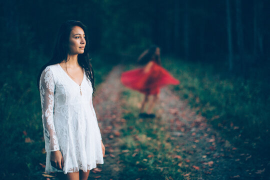 Brunette woman in white lace dress looks into the forest
