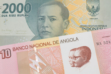 A macro image of a grey two thousand Indonesian rupiah bank note paired up with a colorful ten kwanza bank note from Angola.  Shot close up in macro.
