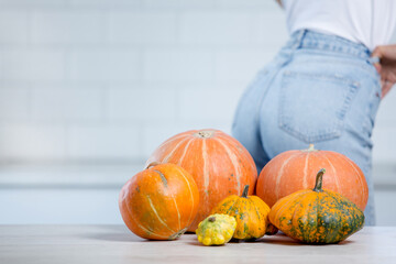  Woman standing in white kitchen wearing jeans and in front of her piles of pumpkins