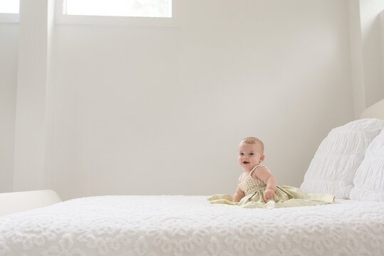 Baby Girl In Nice Dress Alone On A Bed