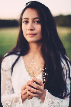 beautiful young woman hold wildflower in her hands