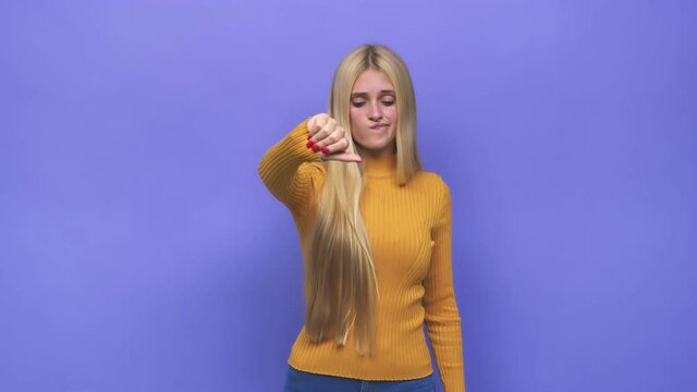 Young caucasian blonde woman showing a dislike gesture, thumbs down, disagreement concept