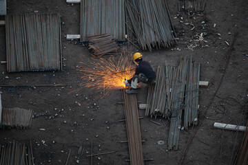 Industrial worker sawing metal with many sharp sparks