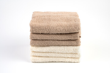 Terry towels are white and light brown on a white background. The view from the top. The concept of home textiles.