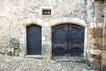 Fototapeta na wymiar Perouges, France - 6/8/2015: Two rustic doors along a cobblestone street in the historic walled city of Perouges
