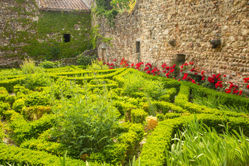A knot garden adjacent to a stone building in the historic walled city of Pergois, France.